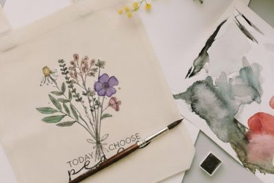 A watercolor painting of flowers on a plain white tote bag